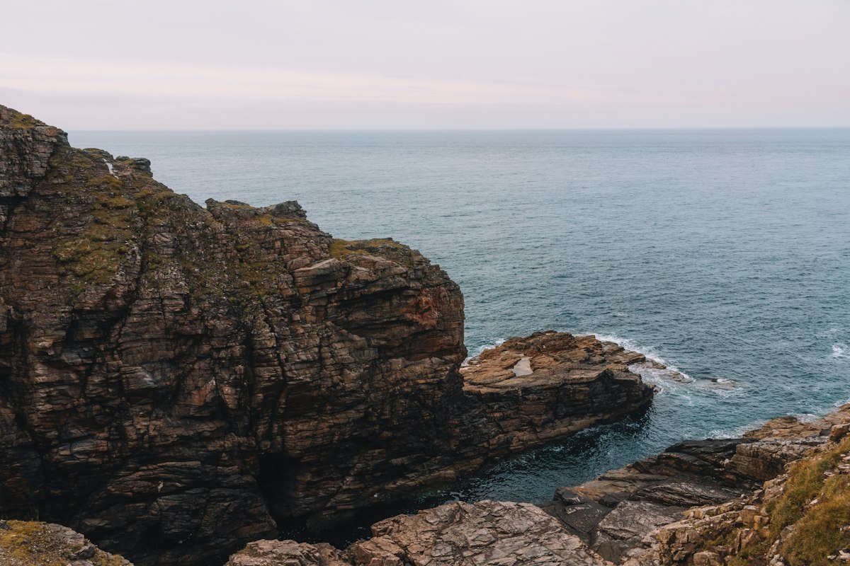 A rocky coastal headland overlooking a calm sea at dusk